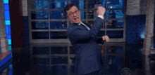a man in a suit and tie is dancing on a stage while wearing glasses .