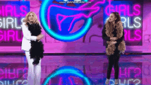 two women standing on a stage in front of a sign that says girls