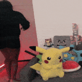 a pikachu stuffed animal sits on a couch in front of a wall with posters of kanye west on it