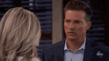 a man in a suit and tie is looking at a woman in a pink shirt .