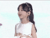 a little girl wearing a white dress and a headband with pearls