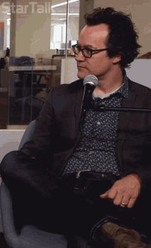 a man sitting in front of a microphone with startalk written on the bottom right