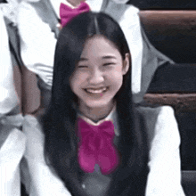 the girl is wearing a pink bow tie and smiling .