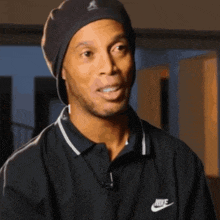 a man wearing a black nike polo shirt and a black hat