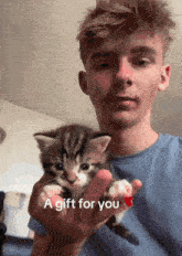 a man is holding a small kitten with the words " a gift for you " below him