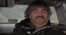 jack black is driving a car and smiling .