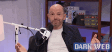 a man with a beard is sitting in front of a microphone with the words dark web on the bottom .