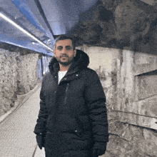 a man in a black parka stands in a tunnel