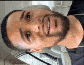 a close up of a man 's face with a beard and a chain around his neck