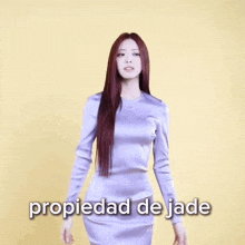 a woman with red hair is standing with her arms crossed in front of a yellow background with the words propiedad de jade written below her