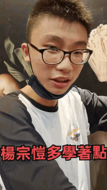 a young man wearing glasses and a face mask with chinese writing on the bottom