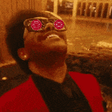 a man wearing sunglasses with red circles in his eyes is smiling
