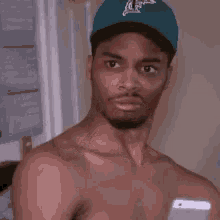 a man without a shirt is wearing a blue baseball cap .
