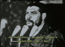 a man with a beard is speaking into a microphone with the words of a revolutionary or a supporter