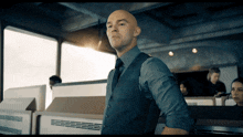 a bald man in a suit and tie is standing in front of a window