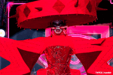a woman in a red costume with spikes on her hat is standing in front of a neon sign that says t4yce tumblr