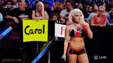 a woman in a wrestling match holds a sign that says carol