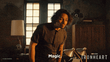 a man in a black shirt is standing in front of a window with the words " magic " on the bottom