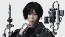 a woman wearing a black jacket and silver bracelets stands in front of a white background