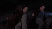 a man and two women are sitting on the ground in the dark