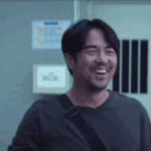 a man with a beard wearing a black shirt is smiling in front of a door .