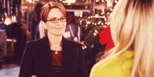 a woman wearing glasses is standing next to another woman in a store .