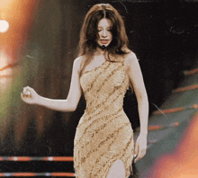 a woman in a gold one shoulder dress is dancing on a stage