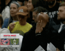 a crowd of people watching a basketball game with a scoreboard that says south west