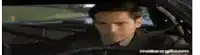 a man in a suit is driving a car .