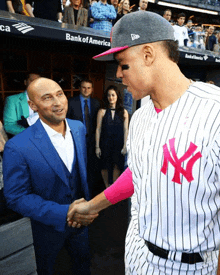 a man in a suit shakes hands with a man in a ny yankees uniform