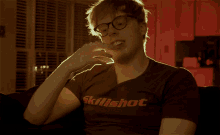 a man wearing glasses and a shirt that says skillshot on it