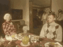 a man and a woman are sitting at a table with food and drinks .