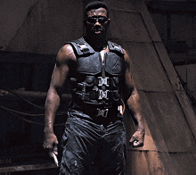 a man wearing sunglasses and a black vest with the letter d on it