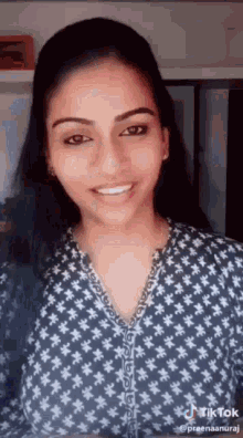 a woman in a blue and white polka dot shirt is smiling .