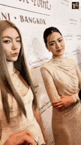 two women are standing in front of a wall that says grande centre-centre