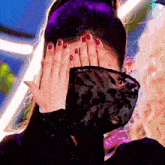 a woman with red nails covers her face with her hands