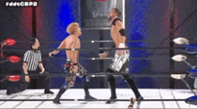 two men are wrestling in a ring with a referee .
