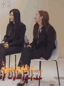 two women are sitting in chairs with a fire behind them that says ohl