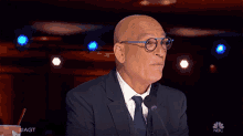 a man in a suit and tie is speaking into a microphone with a cup of soda in the background that says #agt on it