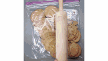 a person is using a rolling pin to smash crackers into a plastic bag .