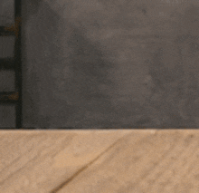 a close up of a cat 's eyes peeking over a wooden table .