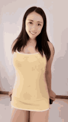 a woman in a yellow tank top and shorts is smiling for the camera