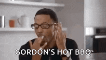 a man wearing glasses is eating a piece of food and says gordon 's hot bbq .