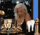 a woman is sitting in front of a table filled with trophies and awards .