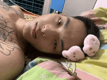 a shirtless man laying on a bed with a stuffed animal on his head