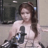 a woman is wearing headphones and sitting in front of a microphone .