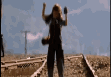 a person is standing on train tracks holding a cell phone