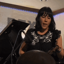 a woman is singing into a microphone in front of a sign that says x