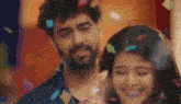 a man and a woman are standing next to each other in a room with confetti falling around them .