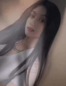 a woman with long black hair wearing a white shirt